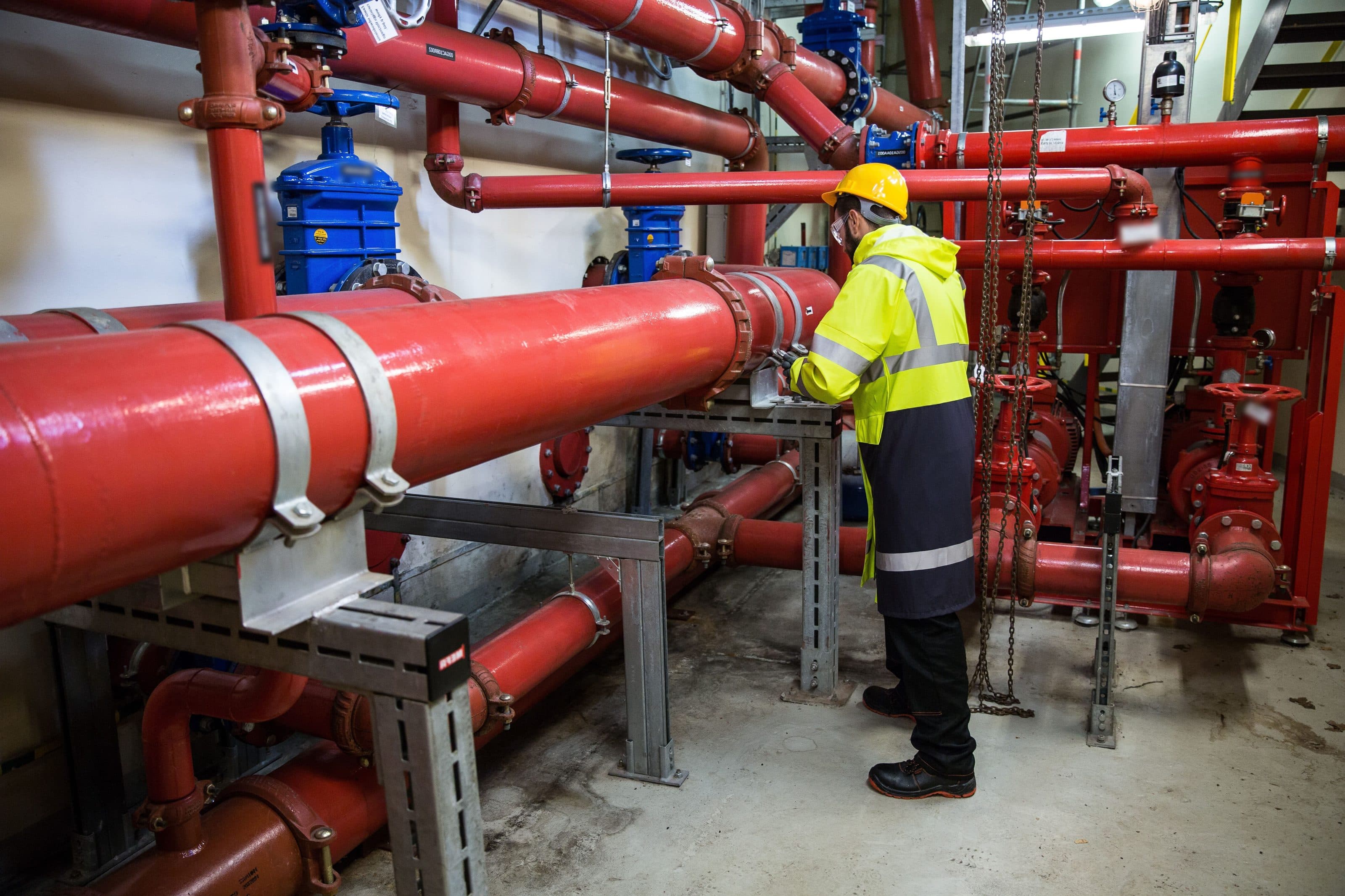 Engineer at the red fire-water mains and pumps of a fire pump room
